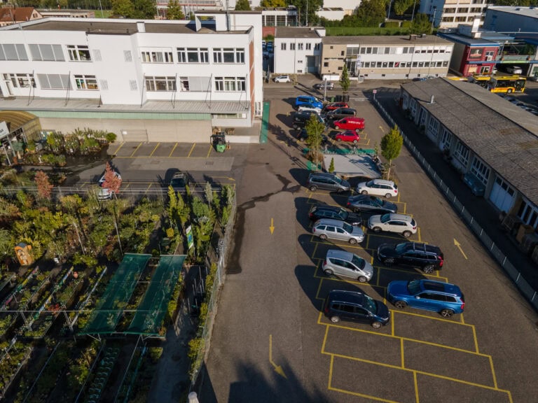 Ein Parkplatz mit Autos und Gebäuden, ideal für Verwaltung oder Gewerbeliegenschaften, bietet flexible Lebensräume für Unternehmen.