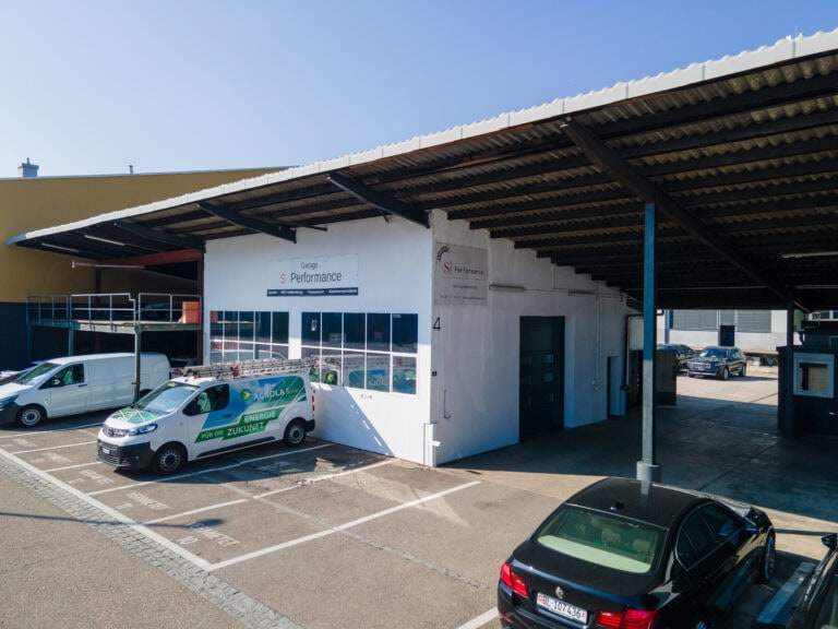 Inmitten von Gewerbeliegenschaften steht eine weiße Autowerkstatt mit der Aufschrift 