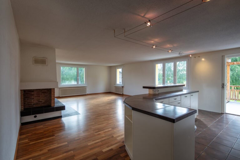 Geräumiger, unmöblierter, offener Wohnbereich mit Holzböden, großen Fenstern, einem Eckkamin und einer Kücheninsel mit dunkler Arbeitsplatte - ideal für die Vermietung. Genießen Sie den Zugang zur Terrasse durch eine Glastür in diesem attraktiven Mietangebot.