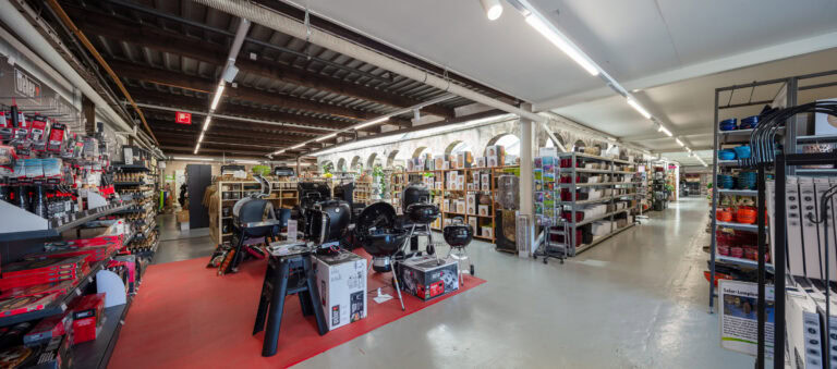 Ein geräumiger Baumarkt mit Regalen voller Werkzeuge, Grills und Heimwerkerartikel. Der Laden bietet helle Beleuchtung, hohe Decken und breite Gänge - perfekt, um Mietangebote zu erkunden, die Ihre Lebensräume verbessern.