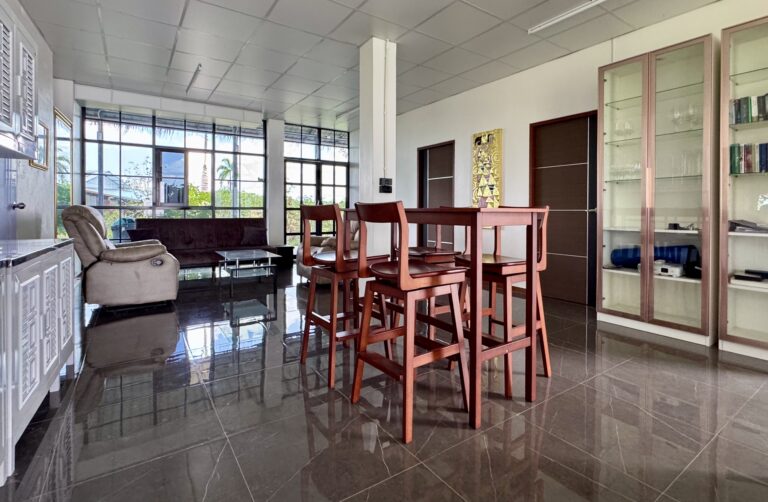 Erleben Sie eine atemberaubende Verwandlung in diesem hellen, modernen Wohn- und Essbereich mit einem Esstisch aus Holz, Glasvitrinen, einem Sofa, einem Sessel und großen Fenstern, die den gefliesten Raum mit natürlichem Licht durchfluten und ein offenes, luftiges Gefühl vermitteln.